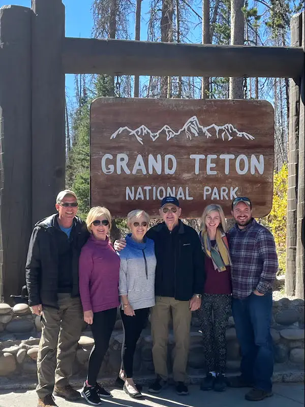 Family standing in front of Grand Teton National Park sign
