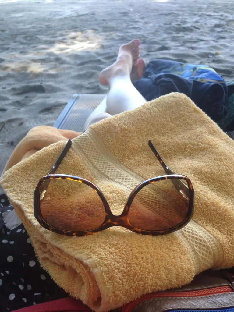 Girl with sunglasses on a beach towel, relaxing in Costa Rica