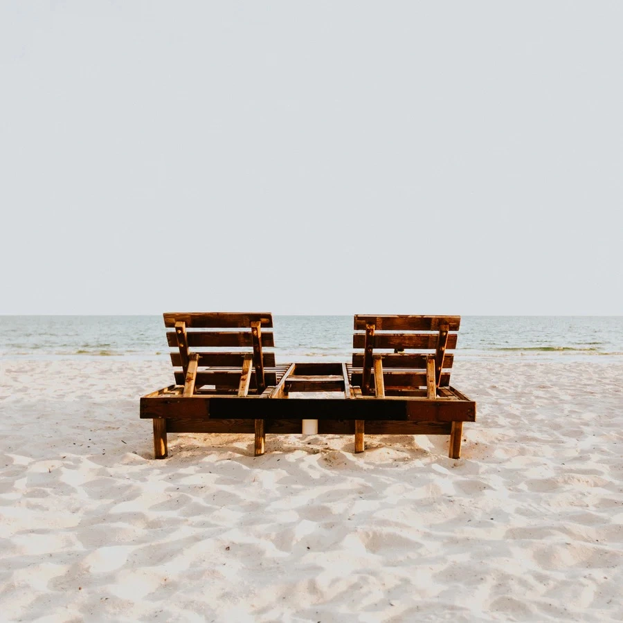 Two Chairs Sitting On Beach In Sand