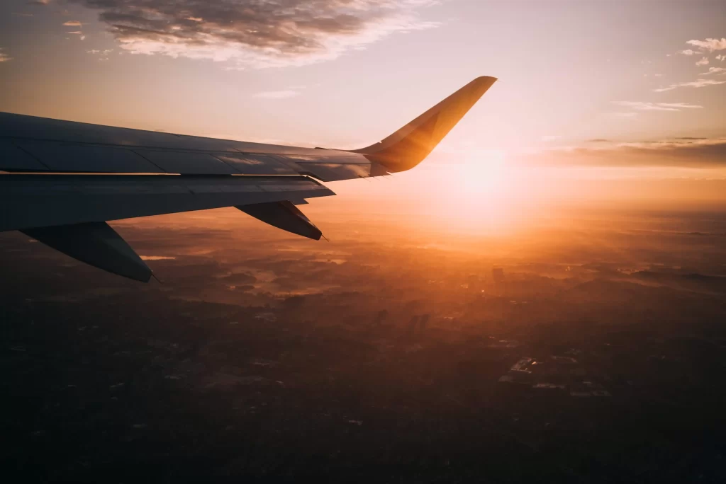 wing of airplane flying in air during sunset