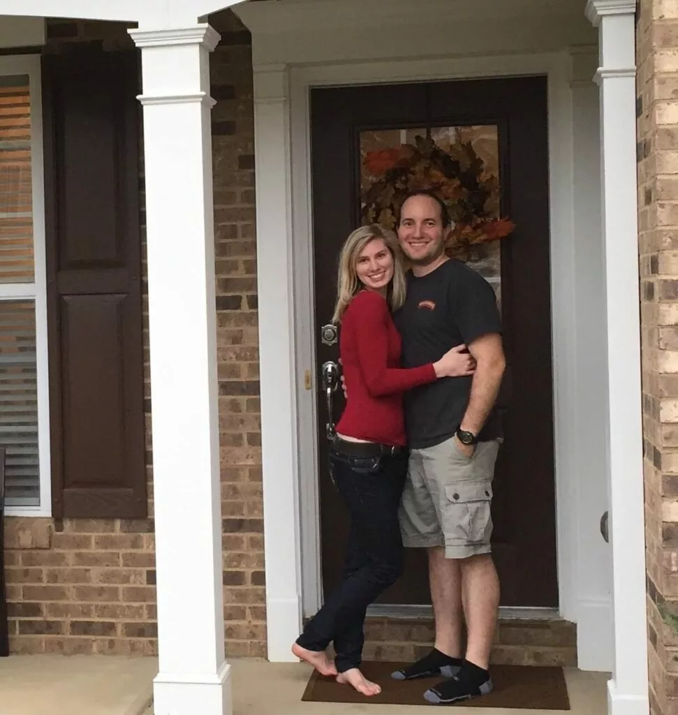 Husband and Wife stand in front of first home 