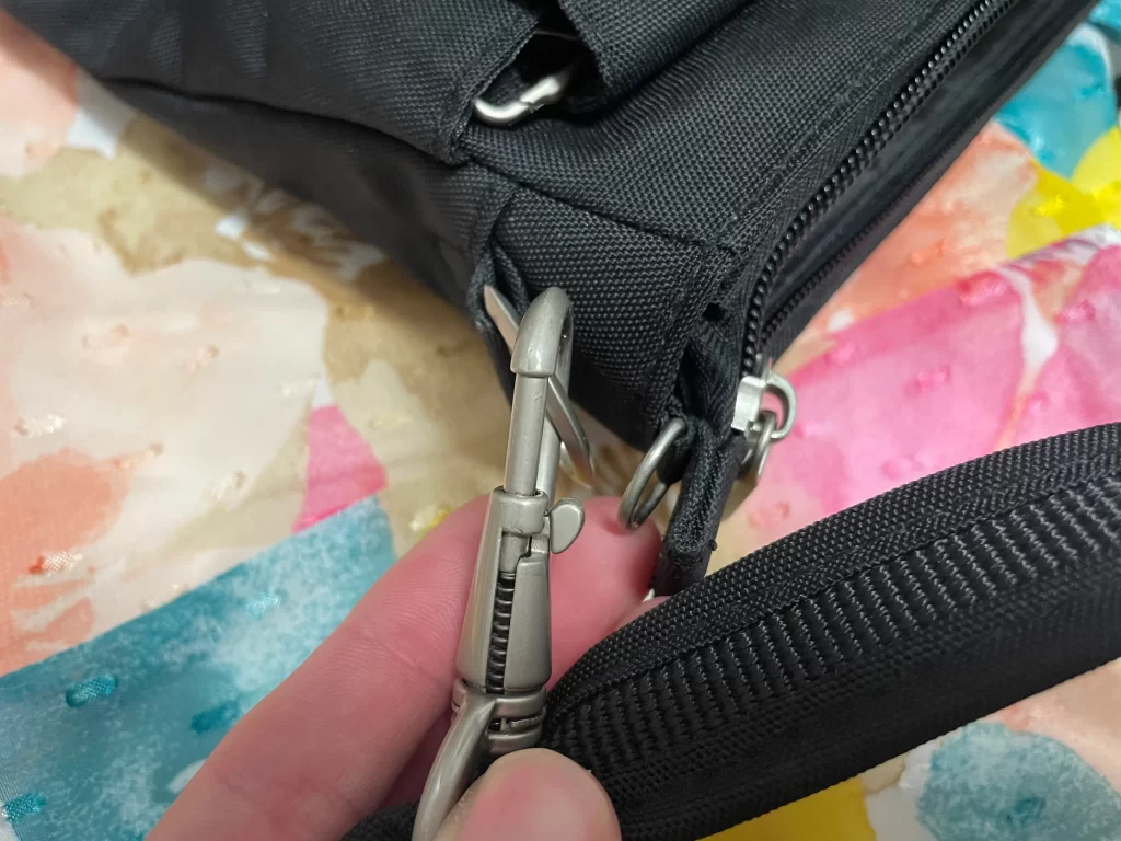 Close up of the lock-down straps on a black classic mini Travelon crossbody bag